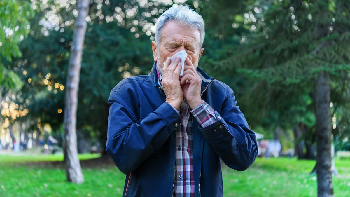 Man with allergies blowing his nose in a tissue