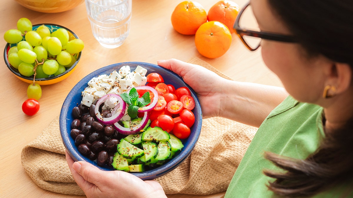Woman holding a healthy Greek salad plate