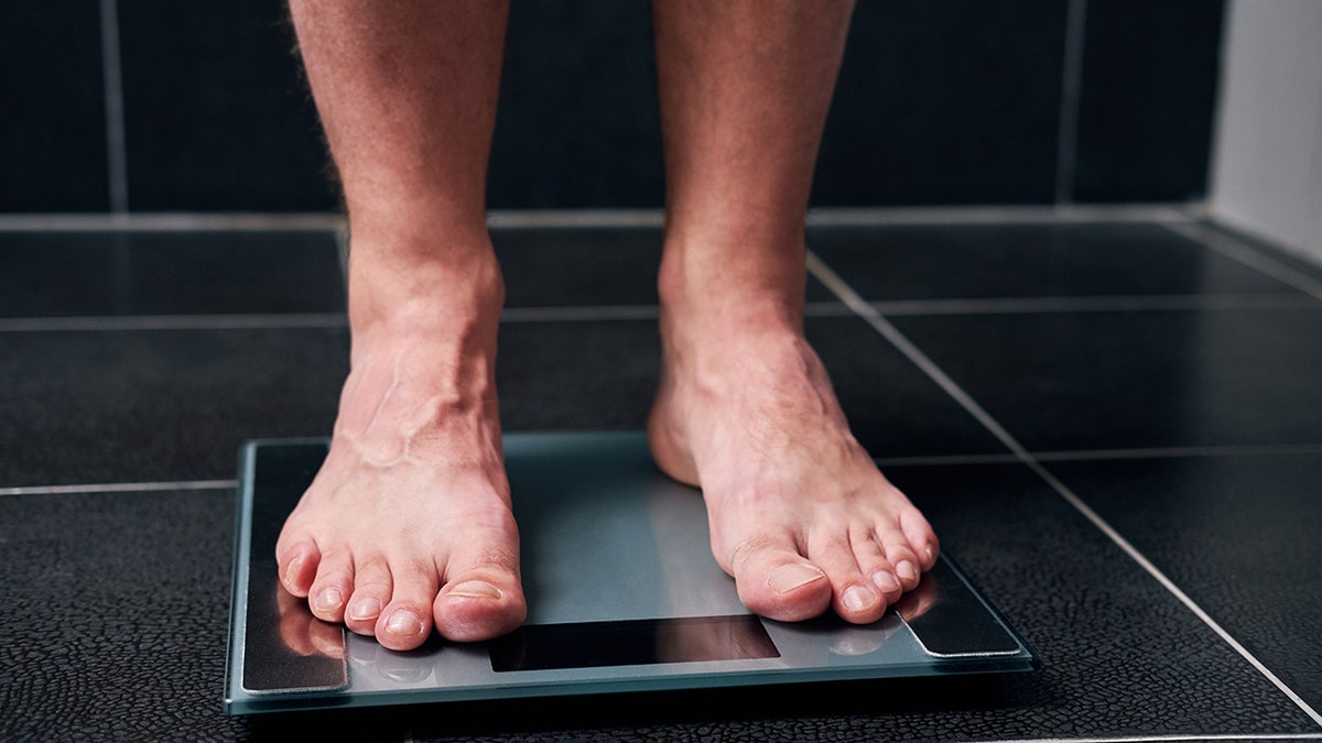Close up on mans feet on a scale as he weights himself