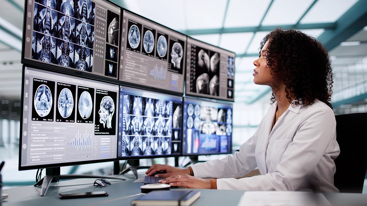 Doctor reviewing patient’s medical scans on monitors for early cancer detection.