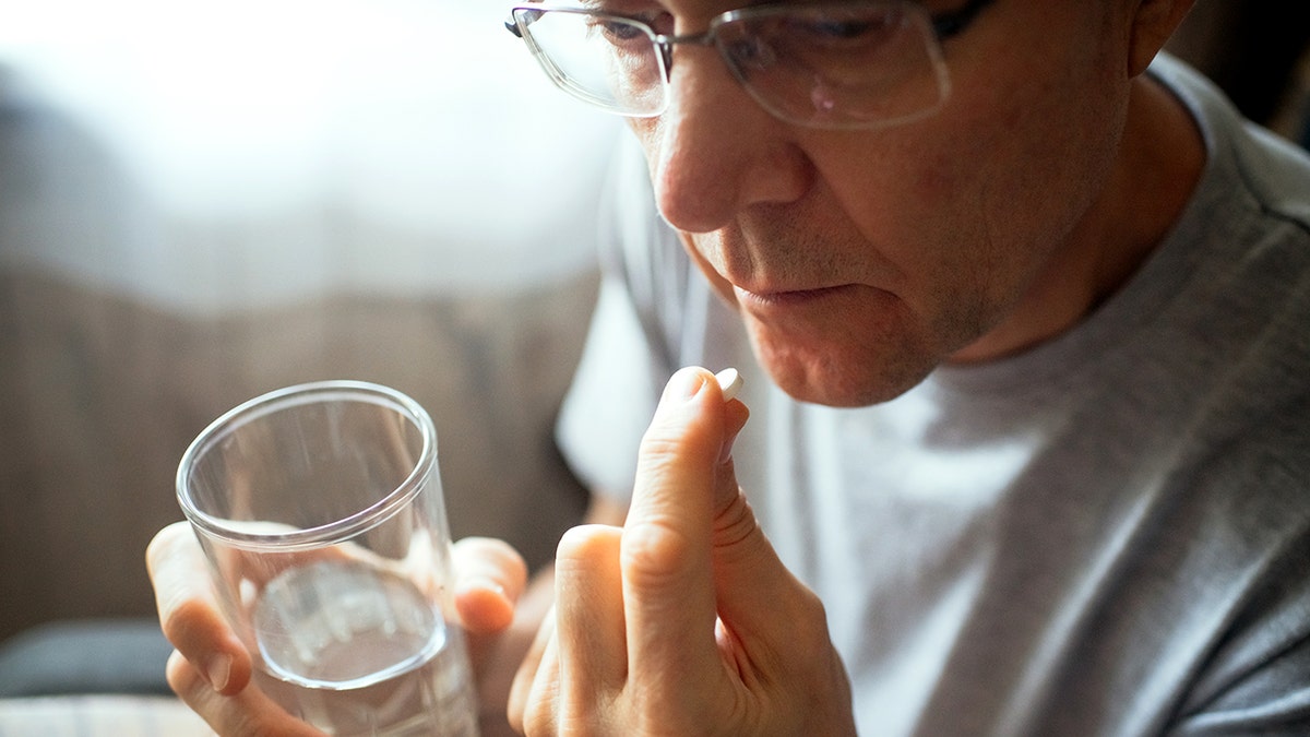 Man taking pill using glass of water