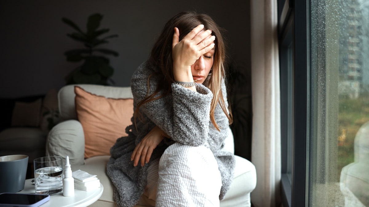 Woman holding head in hands, looking sick to indicate being hungover after night of drinking alcohol