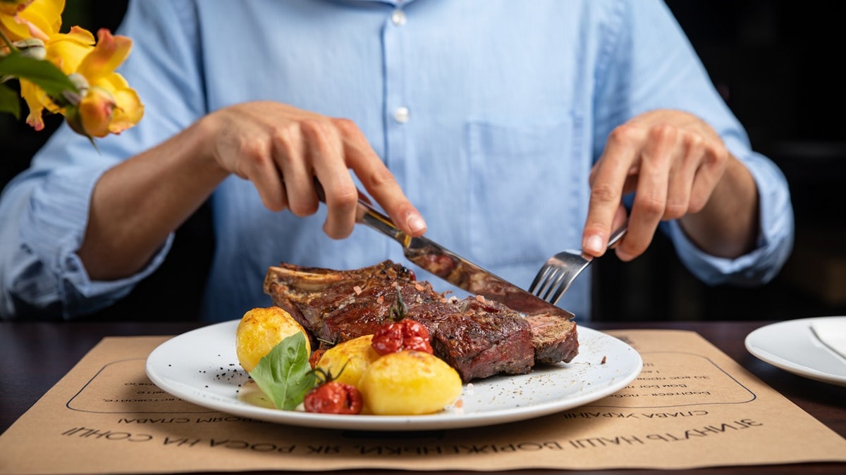 Man eating steak, with other foods on his plate, too