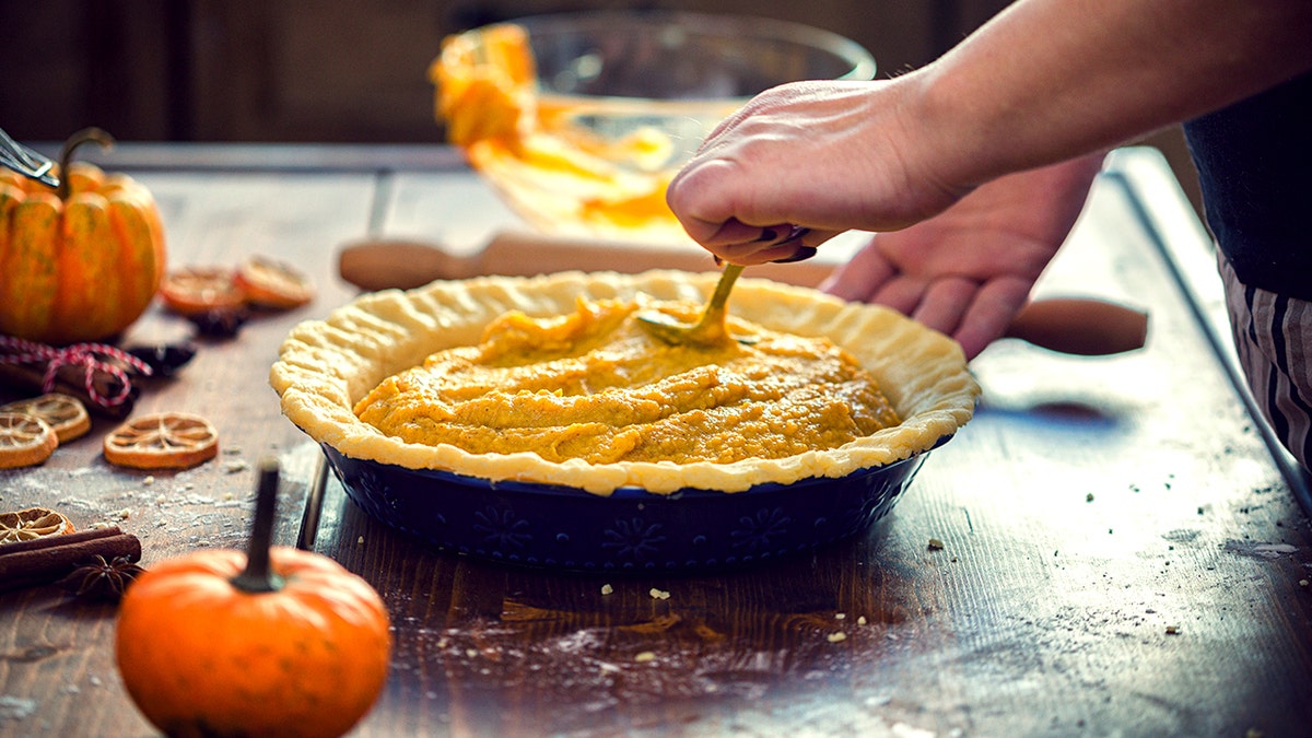 hand tops pumpkin pie off with puree