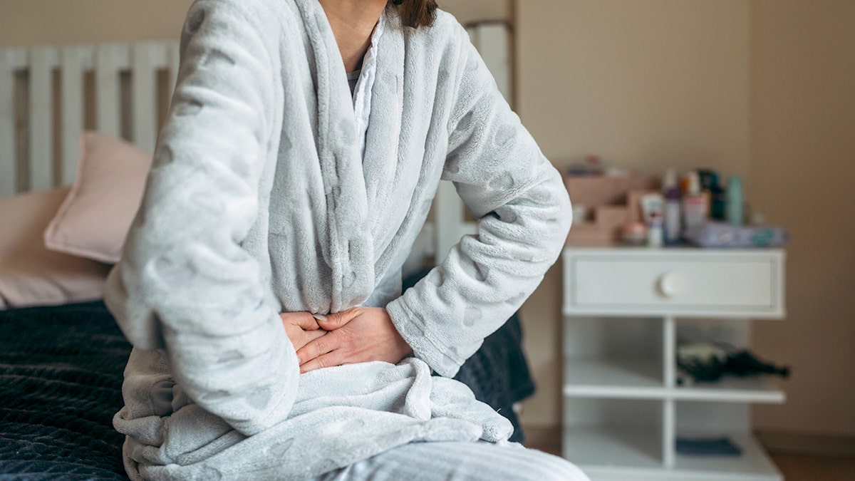 Woman clutching bladder to represent cancer, she is in a bathrobe