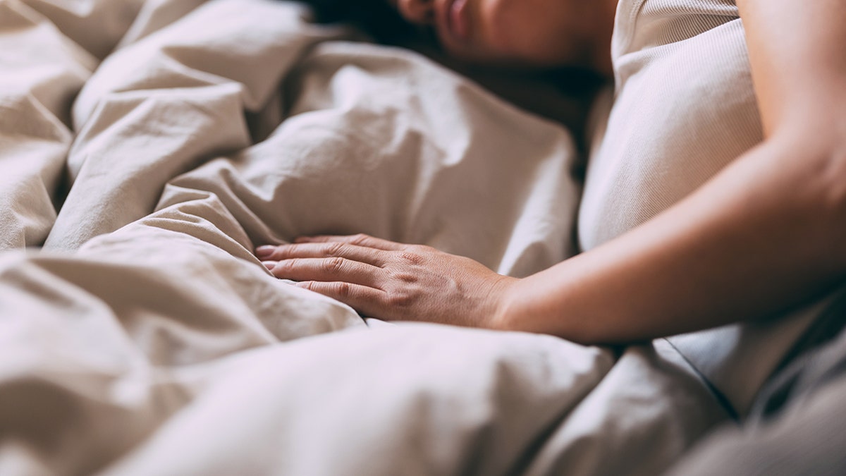 woman's hand rests on top of fluffy comforter
