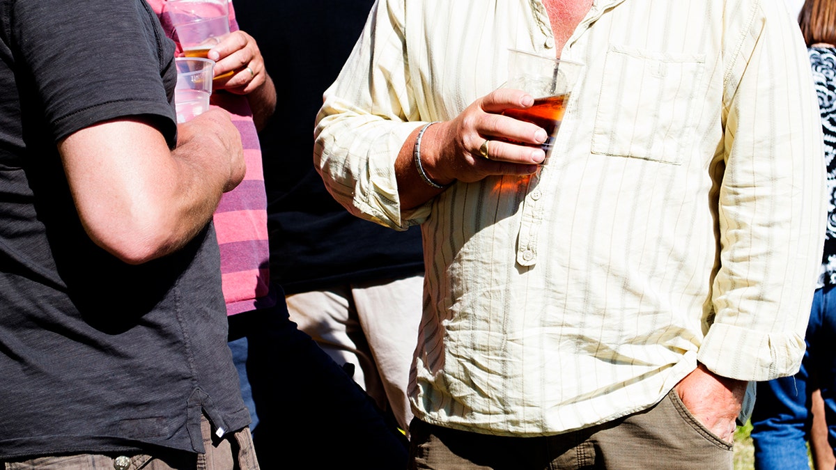 3 men at a summer festival drink beer from plastic glasses