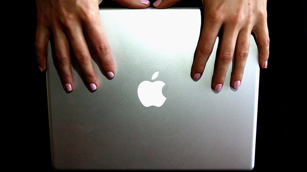 Woman holding an Apple Macbook.