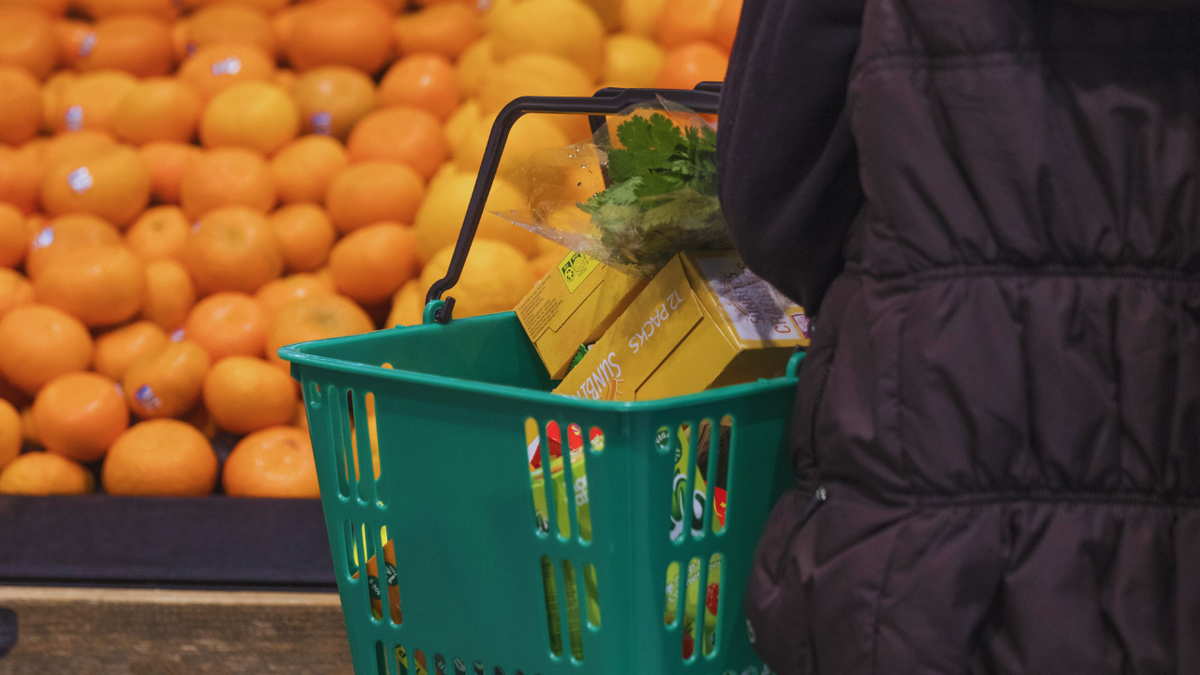 A shopper holds a grocery basket while purchasing food items