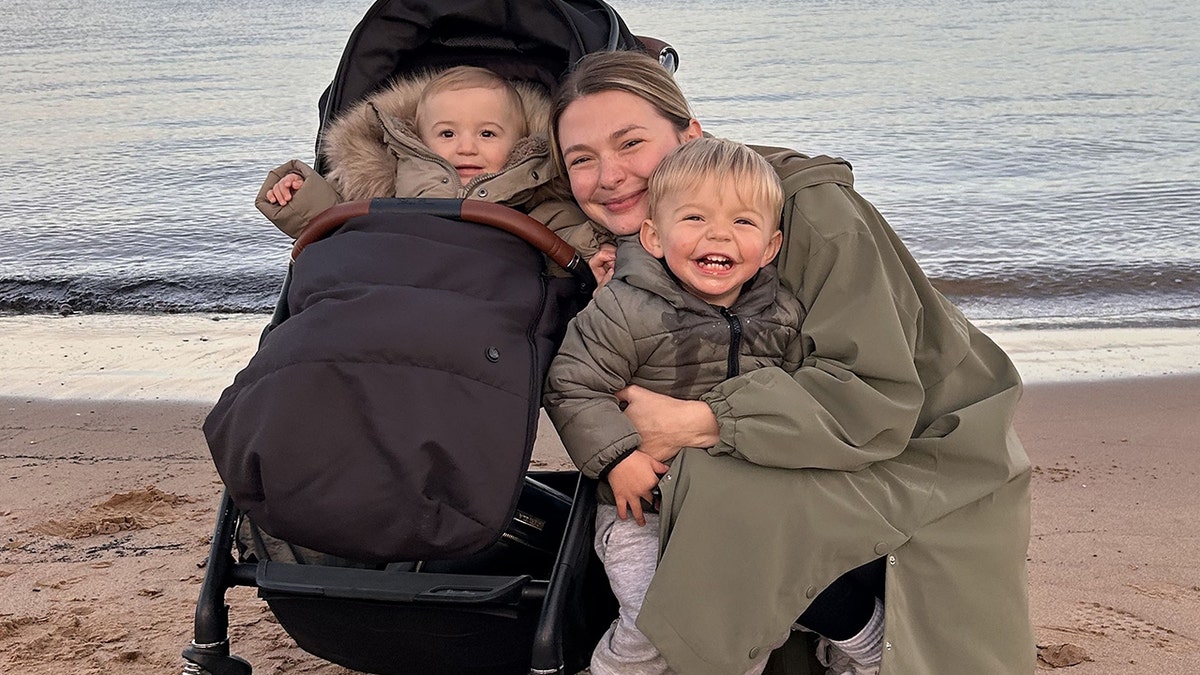 hollie thursby and her two sons on a beach in jackets