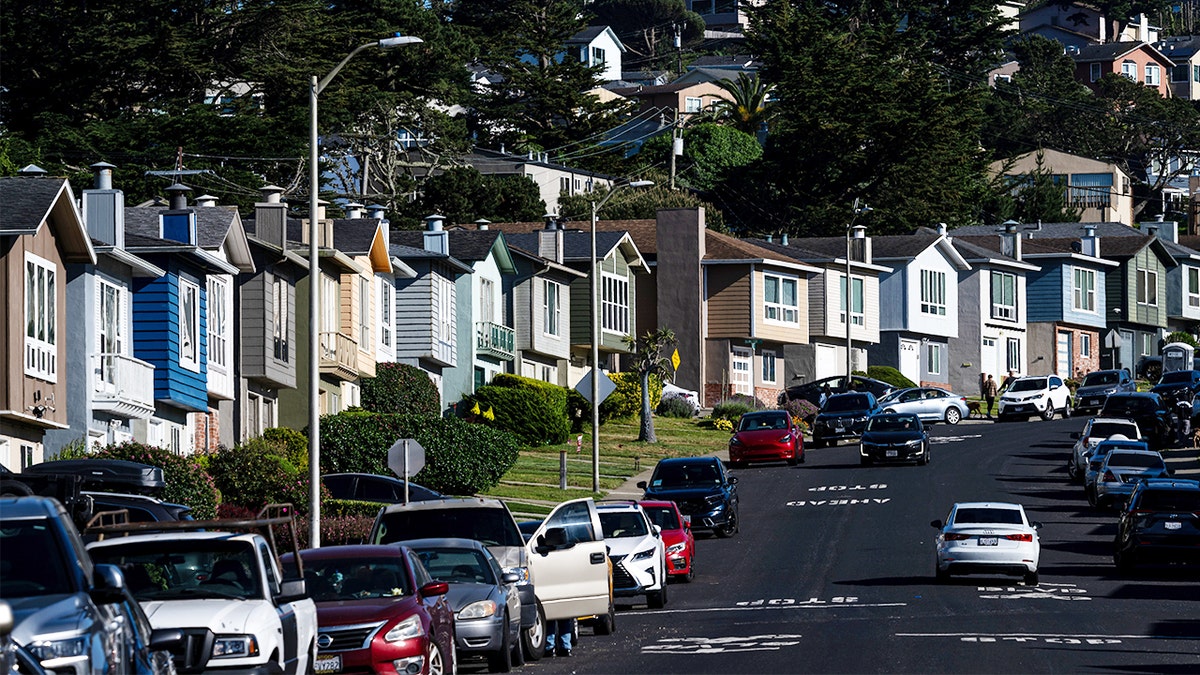 Cars are parked on a street lined with houses.