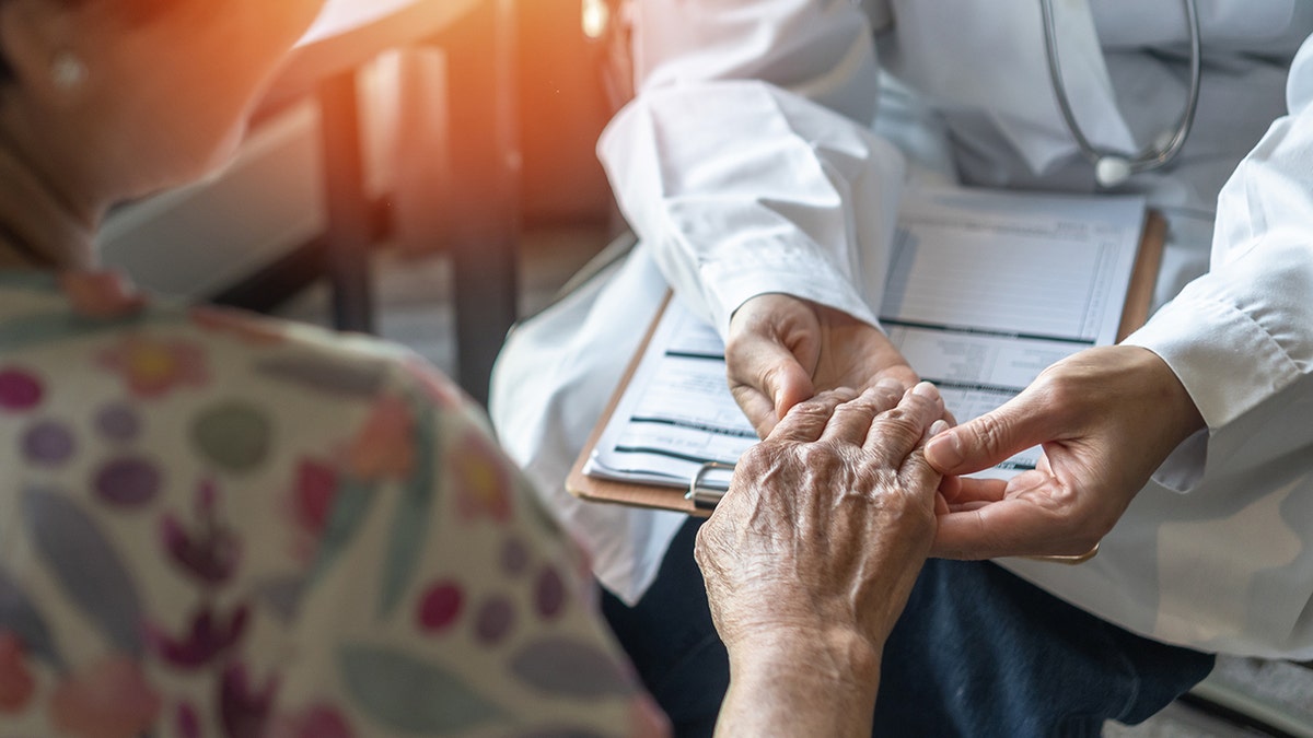 Parkinson's disease patient holding doctor's hand