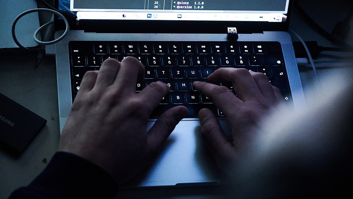 Person typing code on a laptop keyboard