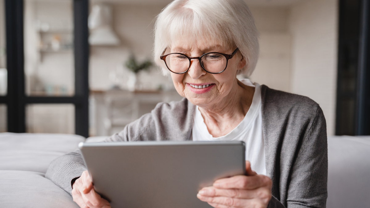 Elderly woman using a tablet while seated at home