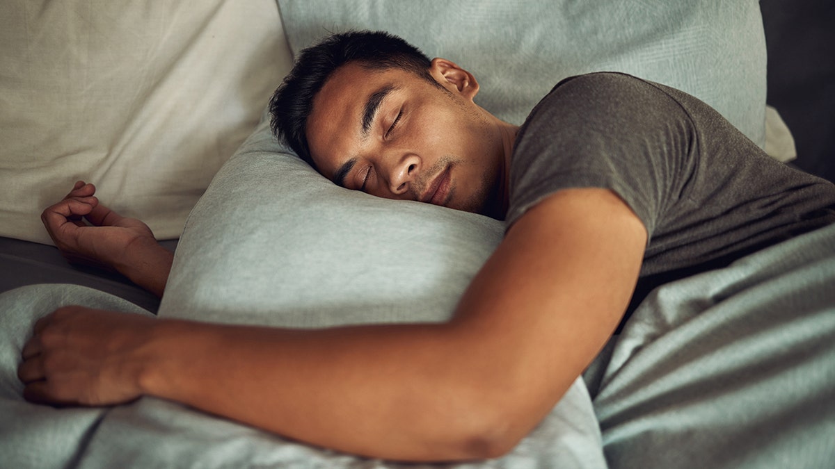 A man sleeping soundly in bed on a pillow.