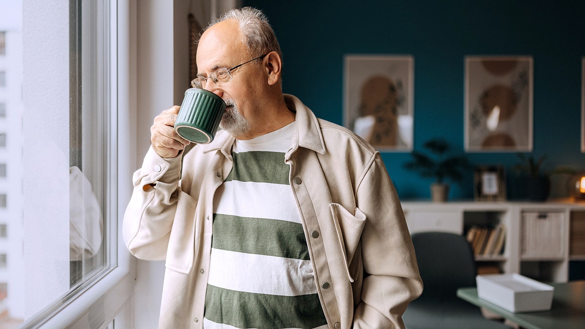 Senior man drinking coffee and looking out a window