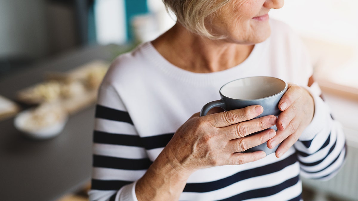 Older woman holding a coffee cup and drinking