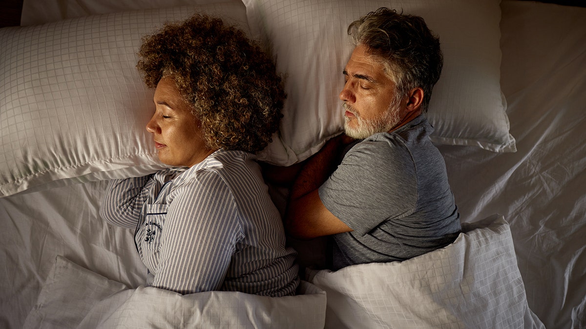 Senior couple sleeping peacefully in a bed from above view
