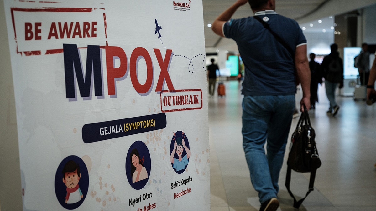 A passenger walking past a monkeypox information banner at Soekarno-Hatta International Airport