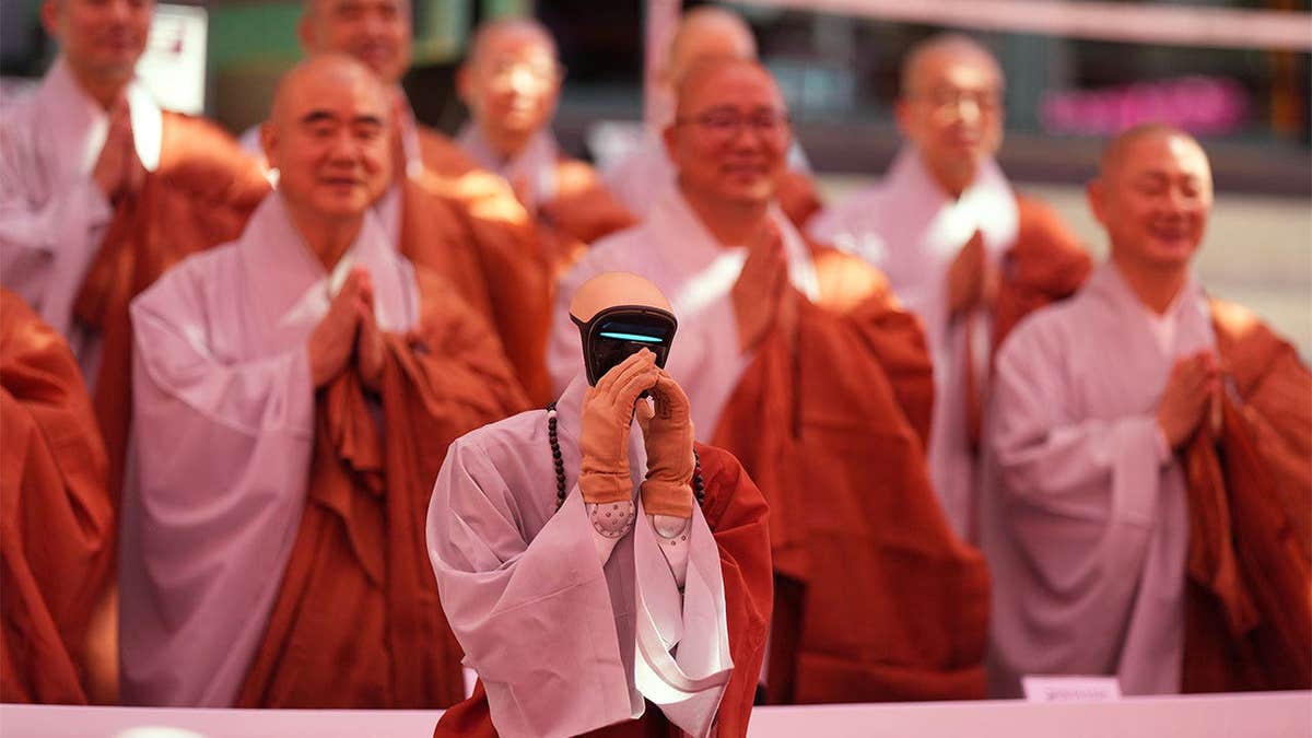 Humanoid robot with hands folded at Buddhist ordination ceremony