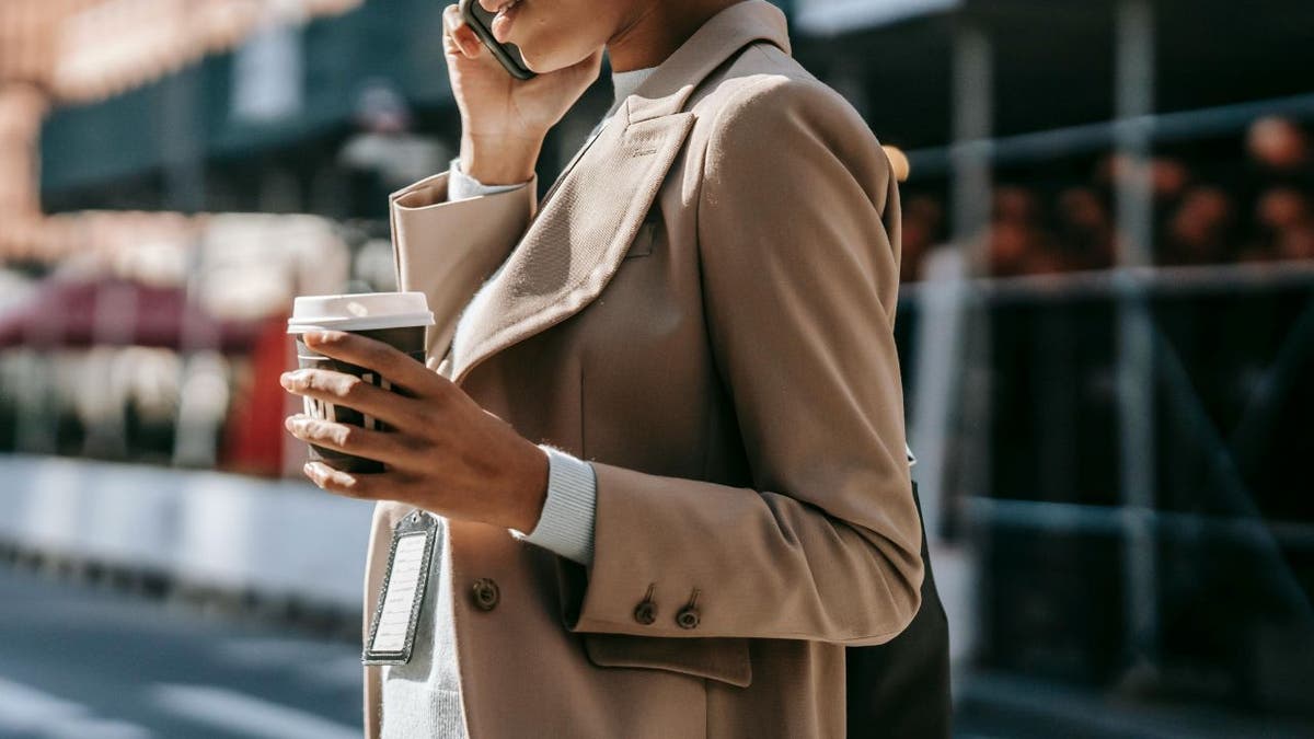Woman talking on the phone while holding a cup of coffee.
