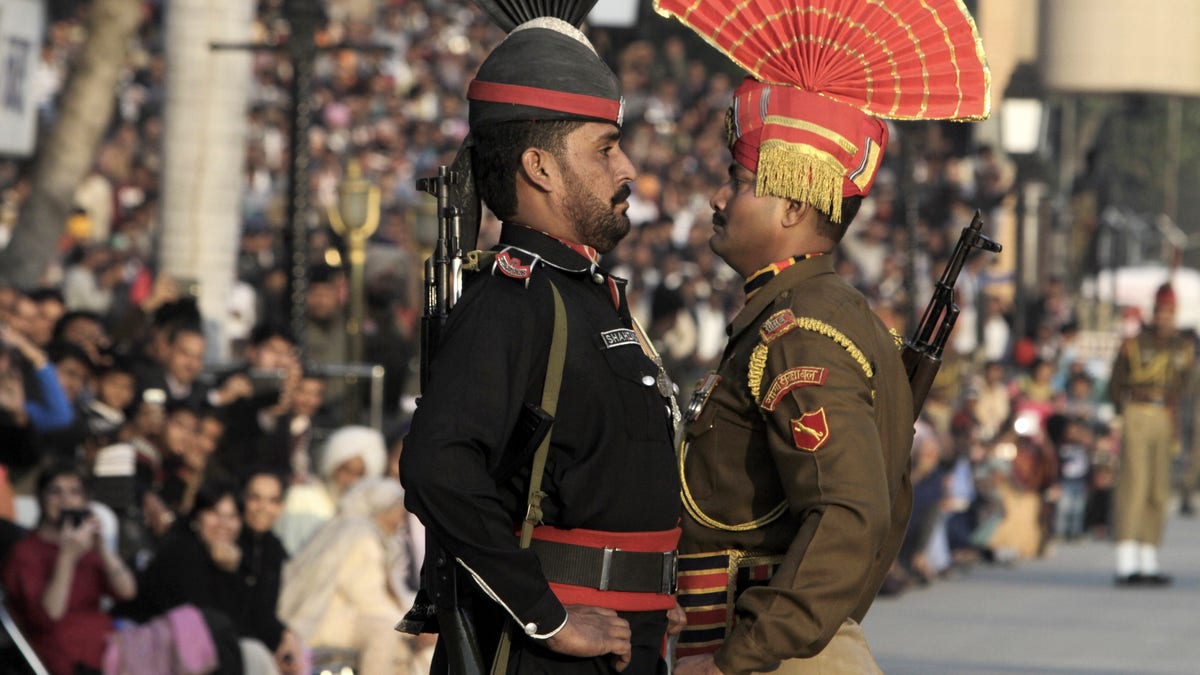 FILE -- In this Friday, Jan. 11, 2013 file photo, a Pakistani Ranger in black uniform and his Indian counterpart, march during a flag off ceremony, at the joint Pakistan-India border check post of Wagah near Lahore, Pakistan. Despite the worst violence in a nearly a decade along the disputed Kashmir border, tension has not spiraled out of control between Pakistan and India, showing just how far the archenemies have come since relations were shattered by the 2008 Mumbai terror attack. (AP Photo/K.M. Chaudary, File)