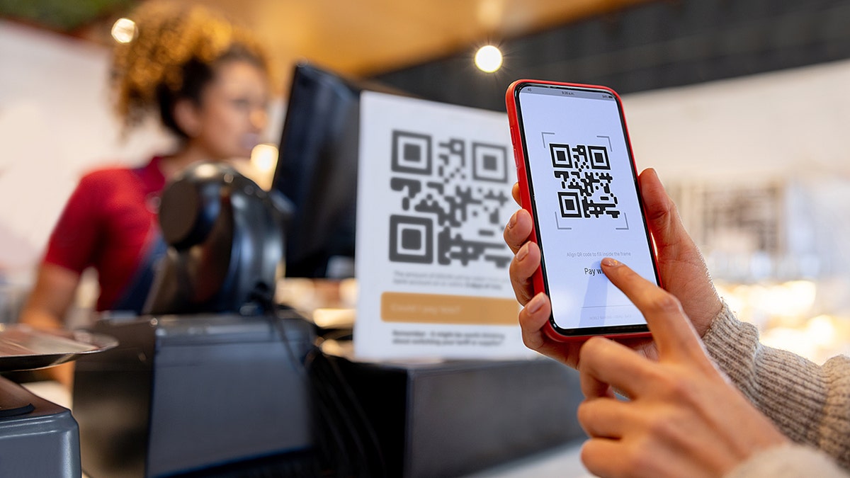 A woman scanning a QR code on her phone for a mobile payment