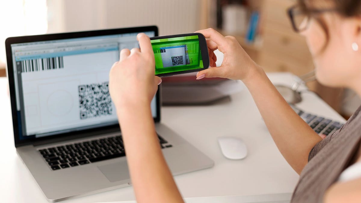 A woman scans a QR code on a computer.