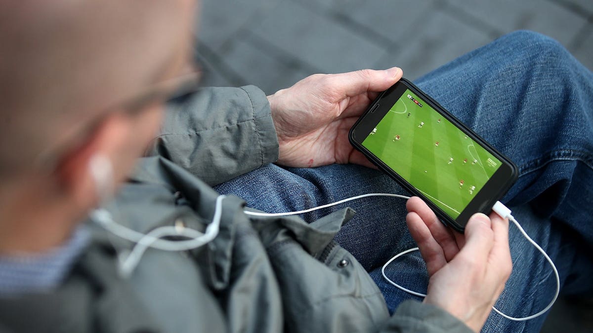 Man streaming the soccer game on his smartphone.
