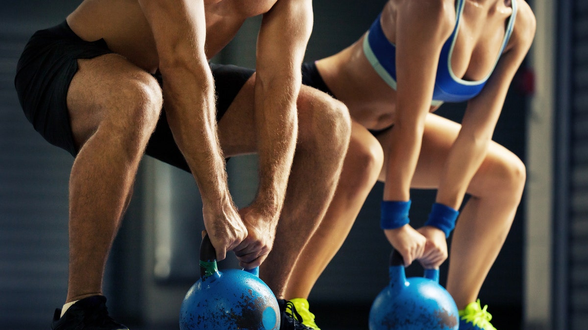 Fit man and woman training by kettlebell.