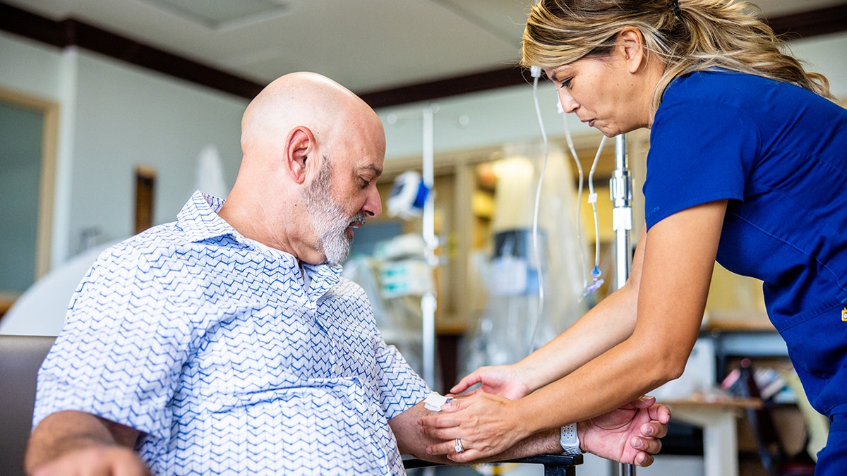 man has IV put into arm by female nurse