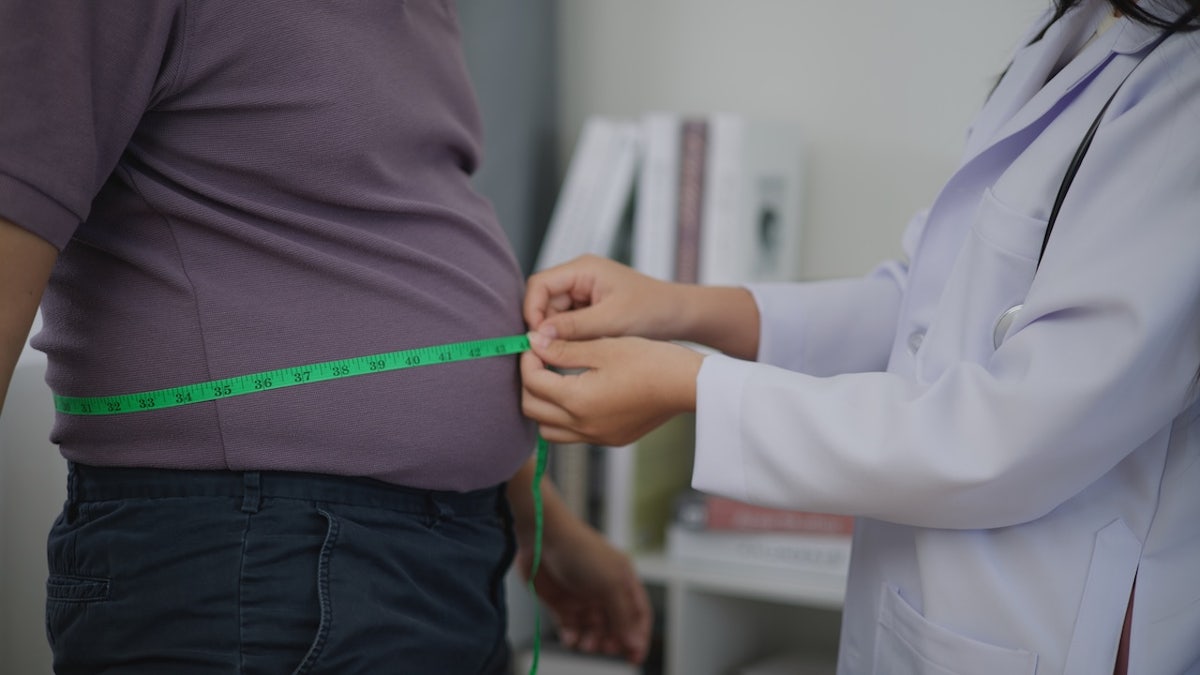 A doctor measures a man's belly fat