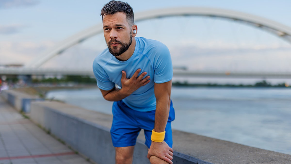 Man holding chest during run.