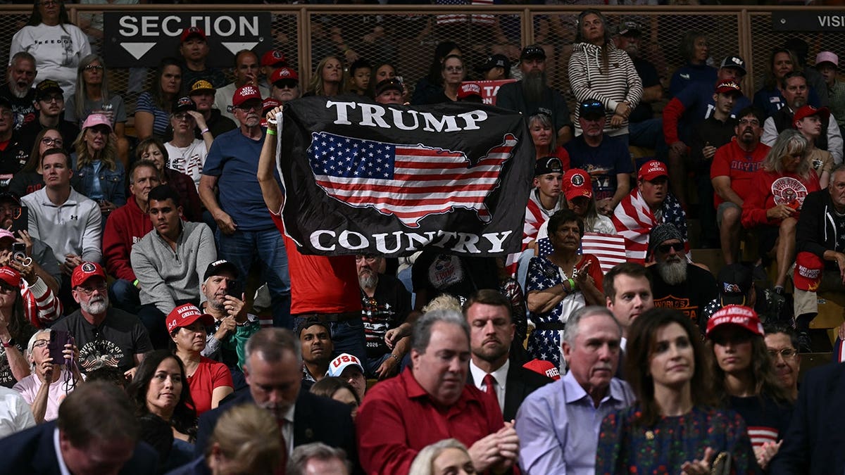 A supporter holds a Trump Country flag as President Donald Trump speaks at a rally in Vandalia, Ohio.