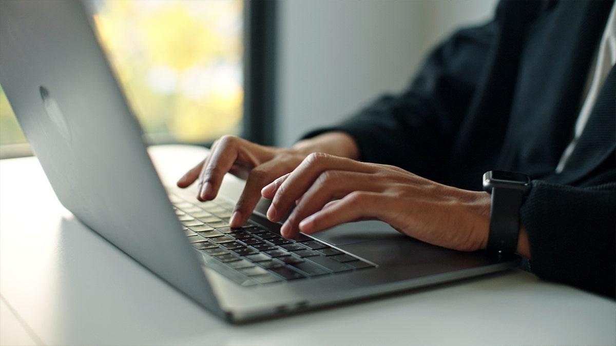 A person types on a laptop.